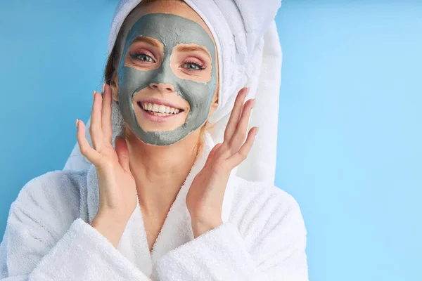 Schöne Frau mit Handtuch auf dem Kopf trägt Maske auf Gesicht auf — Stockfoto