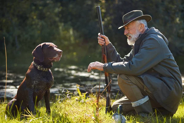 Homem caçador barbudo olhar para o seu cão — Fotografia de Stock