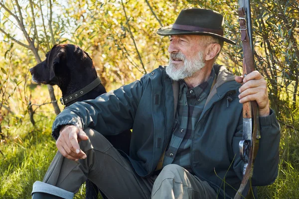 Äldre kaukasiska jägare sitta avkopplande i skogen efter jakt — Stockfoto