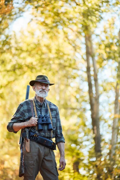 Självsäker jägare med hagelgevär i jaktkläder i höstskogen söker trofé — Stockfoto