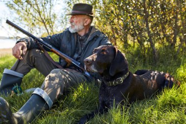 Olgun Kafkas avcısı çimlerin üzerinde köpekle oturuyor.
