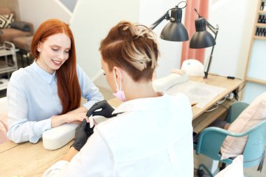 Dost canlısı kadın, manikür ustasına güvenerek bakar.