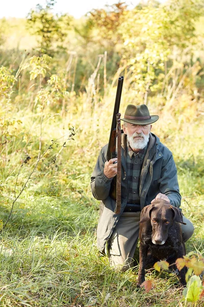 Hunter and his dog looking for trophy in forest