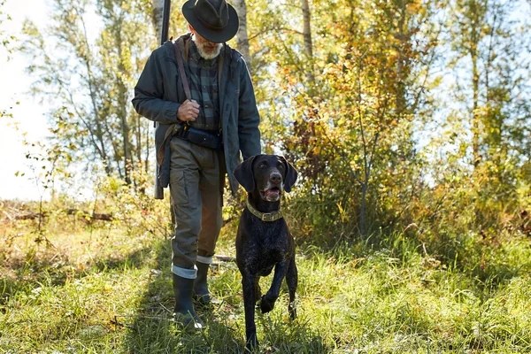 Starší lovec drží psa v lese — Stock fotografie