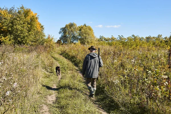 Hunter és kutya megy az úton, a vadászat folyamata a vadászidény alatt — Stock Fotó