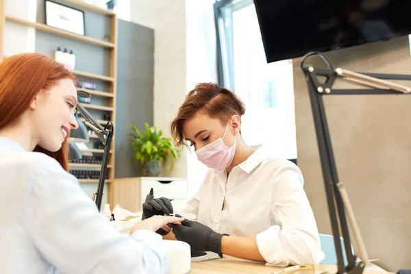 Gelukkig roodharige vrouw doen manicure schoonheid salon — Stockfoto