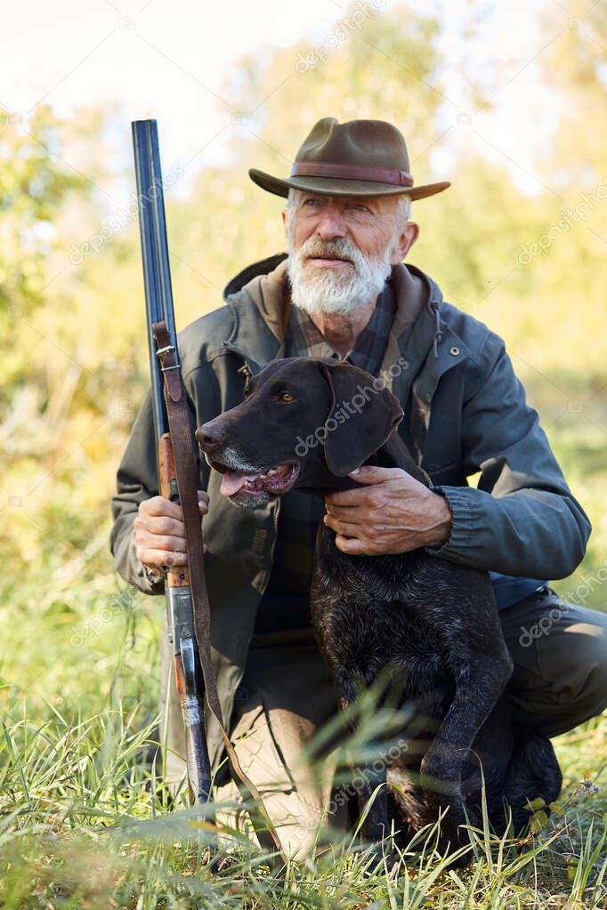 Portrait of senior hunter and dog sit on grass
