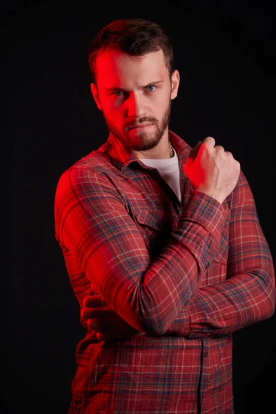 Portrait of young man in casual clothes over black background, neon light on him — Stock Photo, Image