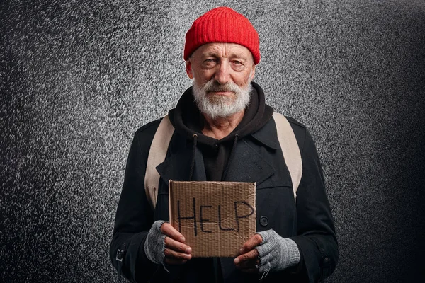 Homem idoso pobre com placa de papelão AJUDA sob chuva — Fotografia de Stock