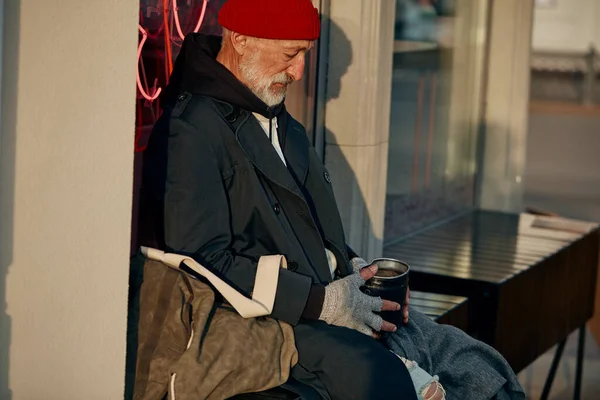 Hombre mayor sentado en el centro de la ciudad pidiendo dinero — Foto de Stock