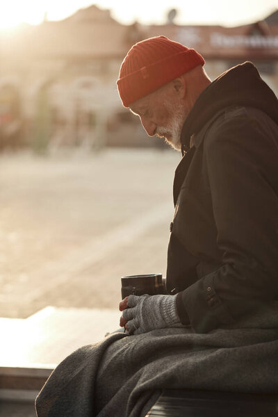 Senior man sitting in the center of city asking for money