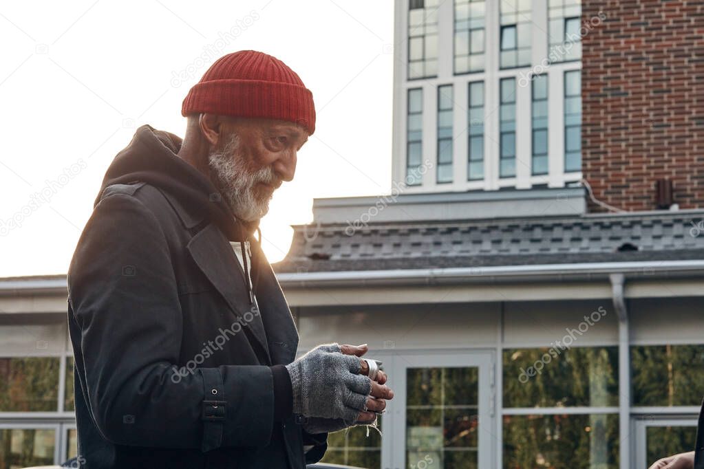 Mature man with grey beard asking for some money by citizens of city