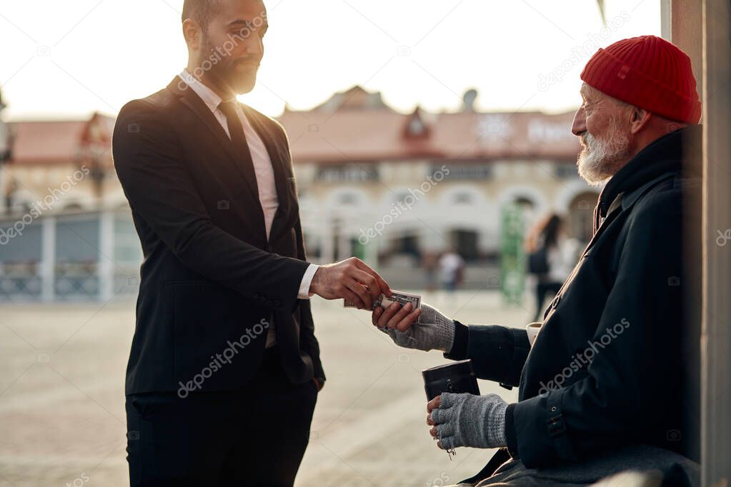 Kind businessman help homeless giving money in street