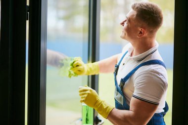 Handyman cleaning panoramic window wearing yellow gloves