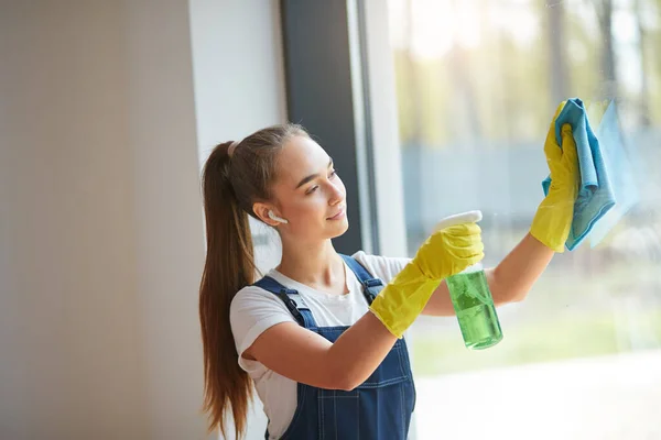 Hermosa joven en guantes amarillos pie ventana de lavado — Foto de Stock