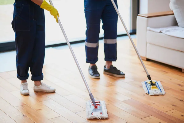 Mensen en huishoudconcept. Twee conciërges benen wassen vloer — Stockfoto