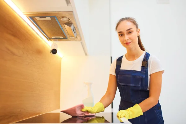 Caucasian girl in blue equipment cleaning plate in kitchen