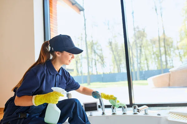 Vrouw met rubberen gele handschoen met vodden wassen en polijsten bad — Stockfoto