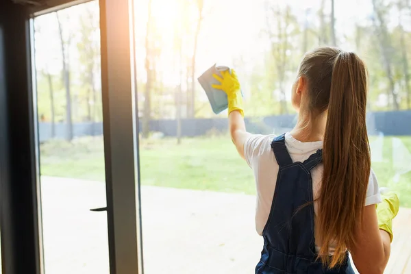 Rear view on young cleaner lady washing glass of window — Stock Photo, Image