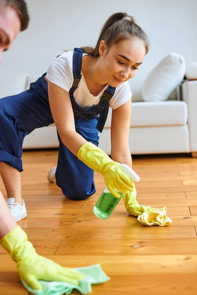 Pozitif kadın temizlik zemini bez ve spreyle cilalıyor. — Stok fotoğraf