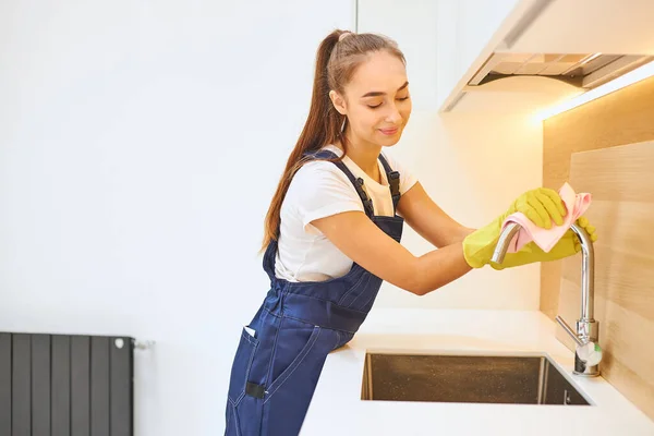 Lächelnde Putzfrau putzt Küche — Stockfoto