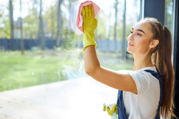 Joven hermosa chica en guantes limpiando vidrio de la ventana —  Fotos de Stock