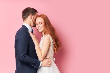 Uzun kızıl saçlı kadın smokinli adamın elini tut.