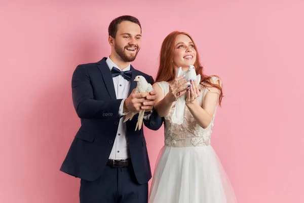 O par alegre de noivo e noiva em conjunto mantém pombos em mãos — Fotografia de Stock