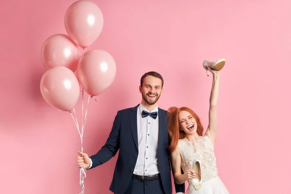 Casal rindo com balões de ar rosa isolado sobre fundo rosa — Fotografia de Stock