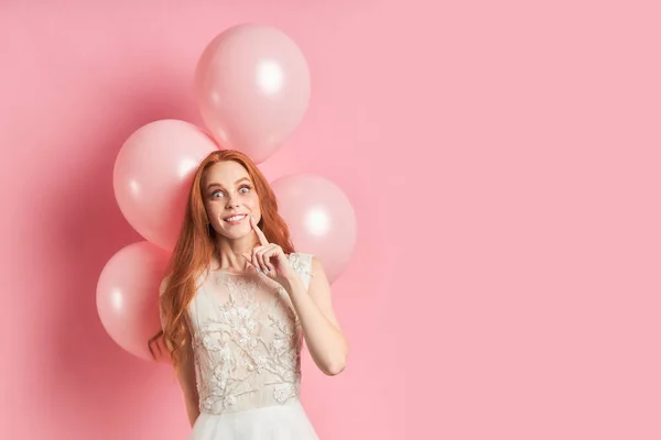 Emotional redhead female in wedding dress on pink background — Stock Photo, Image