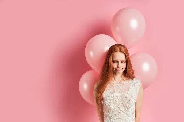 Fille rousse bouleversée en robe de mariée blanche avec des ballons à air — Photo