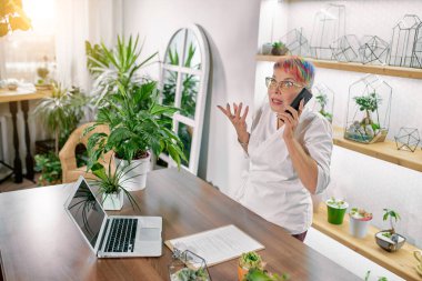 Üst düzey bayan çiçekçi telefonda bir şey anlatıyor.