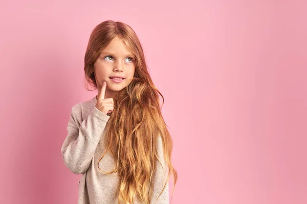 Продумана маленька дівчинка мріє ізольовано на рожевому фоні — стокове фото