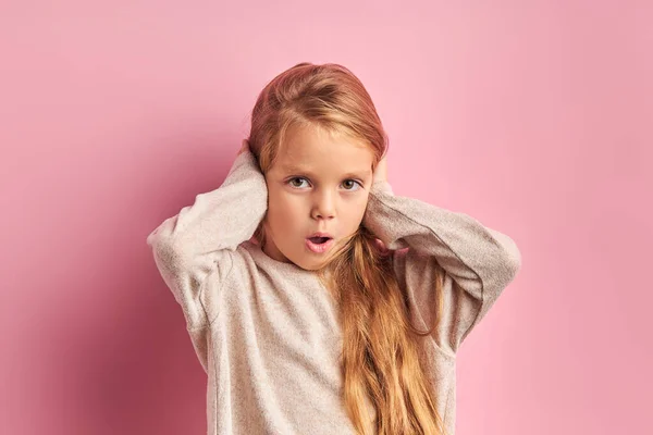 Shocked girl with closed ears look at camera isolated on pink background — Stockfoto