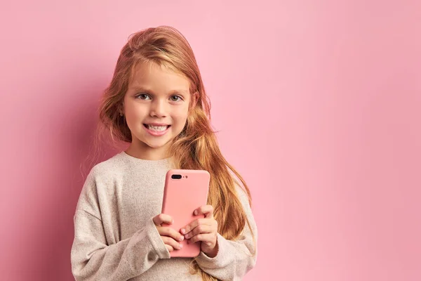 Portret uroczej słodkiej dziewczyny ze smartfonem w rękach odizolowany na różowym tle — Zdjęcie stockowe