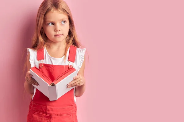 Niña caucásica sosteniendo libro escolar aislado en fondo rosa —  Fotos de Stock