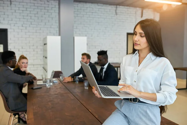 Gorgeous woman in formal wear sit on table using laptop — Stockfoto