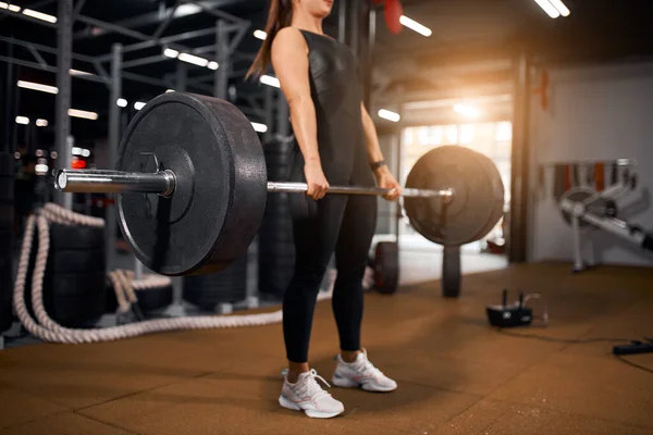 Jonge atletische vrouw doet squats met lange halter — Stockfoto