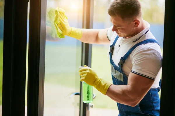 Handyman cleaning panoramic window wearing yellow gloves — 스톡 사진