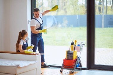 Yeni evi temizleyen genç profesyonel temizlikçiler.