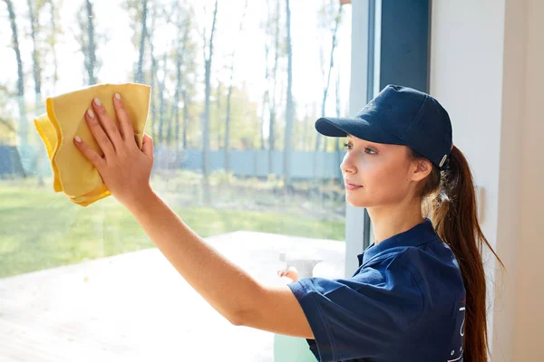 Caucasian woman washes panoramic window wearing uniform