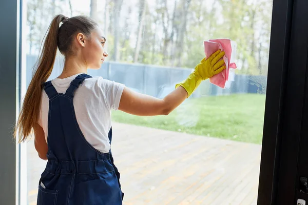 Rear view on young cleaner lady washing glass of window — Stock Photo, Image