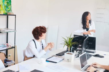 Caucasian woman sitting in white office listening to business plan