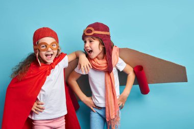 Mavi arka planda pelerinli çocuklara gülüyorlar.