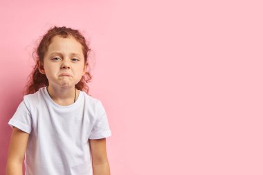 Ağlayan küçük kız, pembe arka planda soyutlanmış.