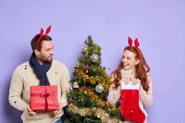 Chica bonita con el hombre cerca del árbol de Navidad — Foto de Stock