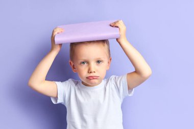 Çocuk okumaktan ve kitabı kafasının üstünde tutmaktan yoruldu.