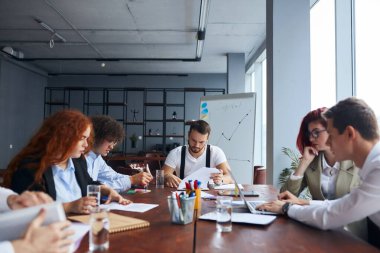 Kafkas iş arkadaşlarından oluşan genç bir ekip modern ofiste büyük iş görüşmeleri yapıyor.