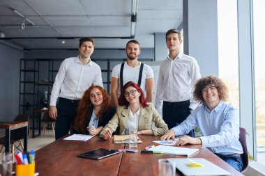 Modern ofisteki masanın yanındaki genç profesyonel iş adamlarının portresi.