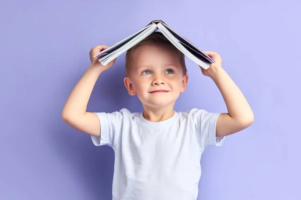 Играющий мальчик, держа книгу над головой — стоковое фото